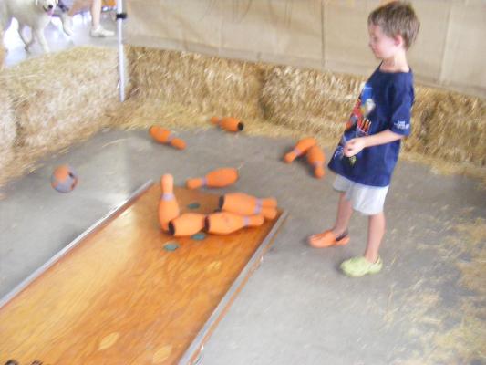 Noah plays bowling at the fair.