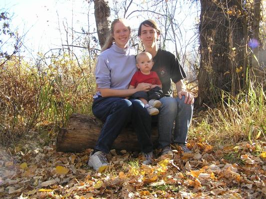 Katie, Noah and David sit on a log.