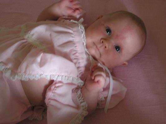 Sarah in her pink dress in her crib.