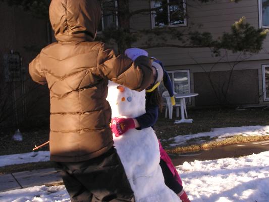 Malia and Andrea play with their snowperson.