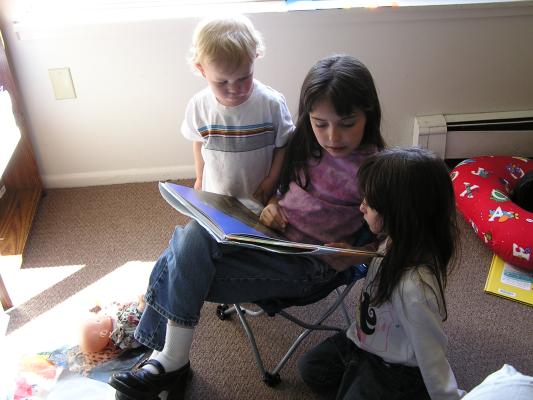 Malia reads a book to Noah and Andrea.