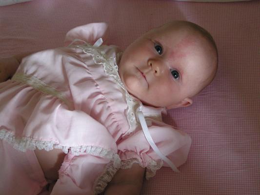 Sarah in her pink dress in her crib.