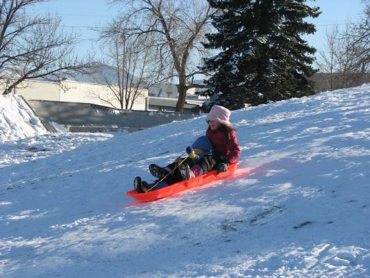 Andrea takes Noah down the hill in the orange sled.