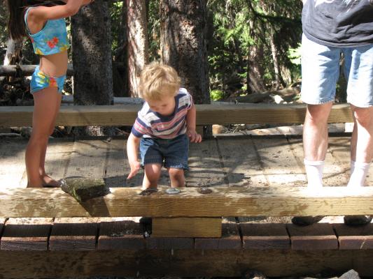 Noah knocks some rocks into the water.