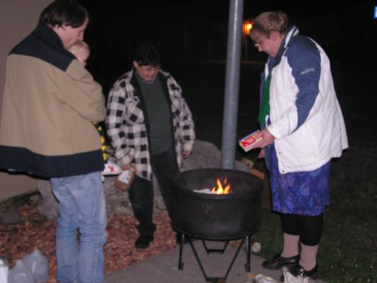 The grownups enjoy the fire outside.