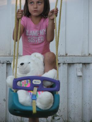 Andrea plays with a bear in a swing. 