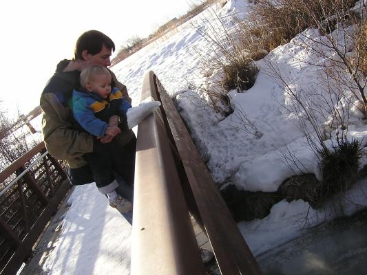 David and Noah throw ice into the river.