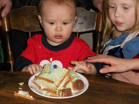 Everyone is making sure he doesn't try to touch the birthday candle.