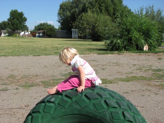 Noah and Sarah at the park in Covered Wagon Mobil home park. Sarah plays on a green tire. 