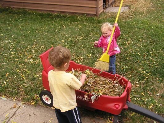 Sarah and Noah play with leaves in the wagon.
