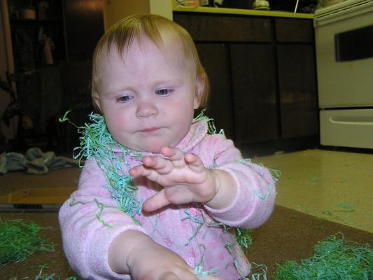 Sarah plays with the green Easter grass.