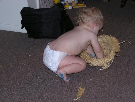 Noah plays with an old straw hat.