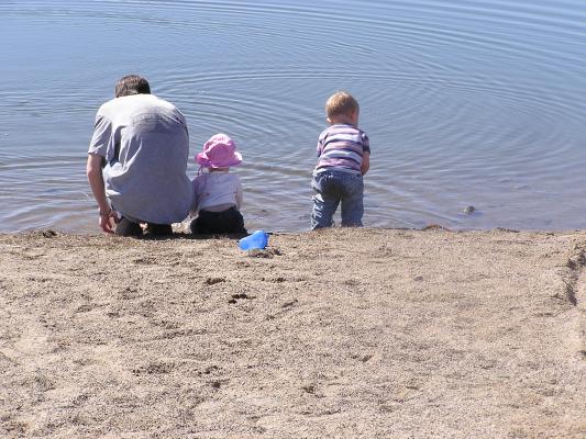 David, Sarah and Noah throw rocks in the water.