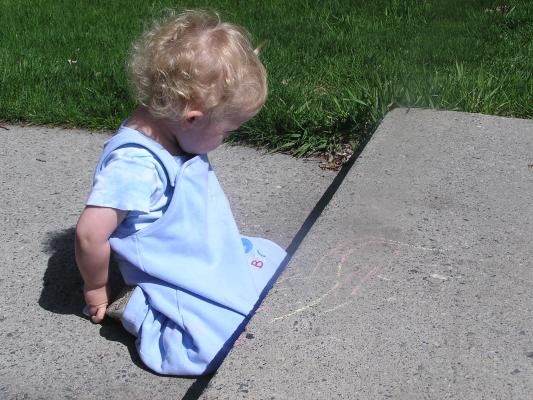 Noah draws on the steps with sidewalk chalk.
