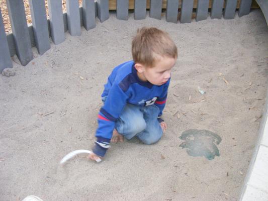 Noah plays in the sand at the Dinosaur park. You can uncover dinosour eggs there.