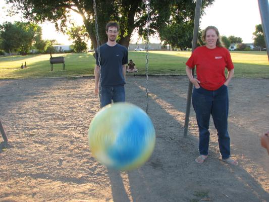 Jim swings the ball. Katie laughs at him,
