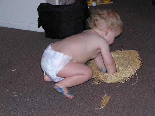 Noah plays with an old straw hat.