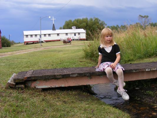 Sarah on a bridge at Little Rockeis with the ponies and the chapel in the background.