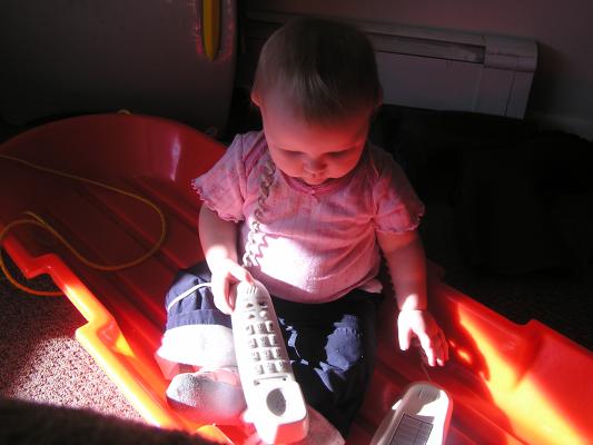 Sarah plays with the phone on the sled.