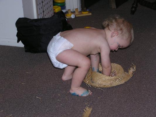 Noah plays with an old straw hat.