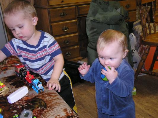 Noah and Sarah play with a train and some cars.