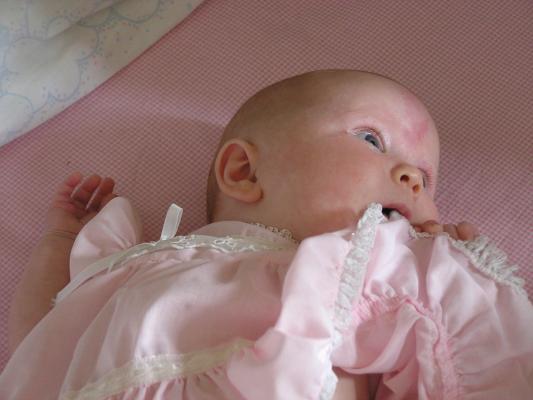 Sarah in her pink dress in her crib.