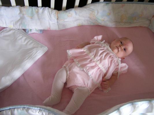 Sarah in her pink dress in her crib.