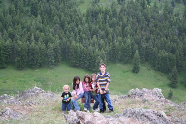 Noah, Malia, Andrea, Nicole and Michael sit on the end of the trail sign.