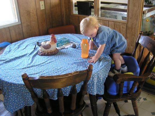 Sarah drinks in the kitchen from a orange bottle
