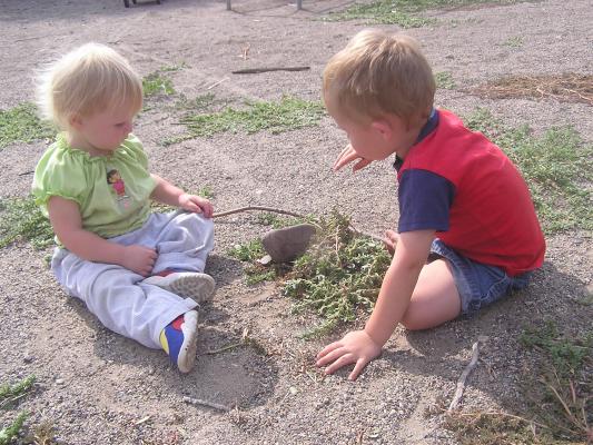Sarah and Noah playing with some weeds at the park.