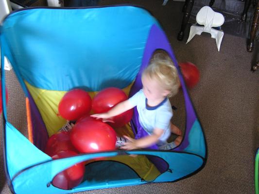 Noah plays with baloons in his tent.