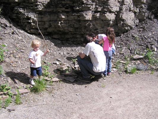 Noah with his stick and David, Andrea and Myke look at rocks.