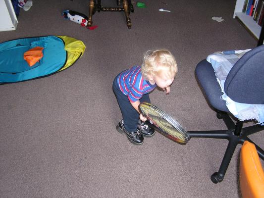 Noah wears Malia's shoes and looks for a ball to hit with the racket.