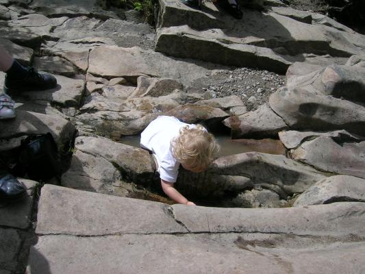 Noah goes wading at the top of the waterfall.