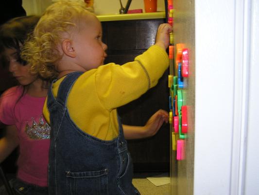 Noah plays with the letters on the fridge.