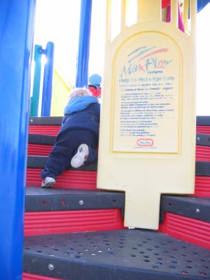 Noah climbs up the playground equipment.