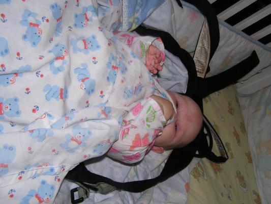 Sarah is awake in her crib in her carier.