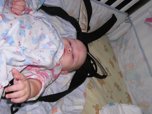 Sarah is awake in her crib in her carier.
