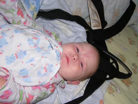 Sarah is awake in her crib in her carier.
