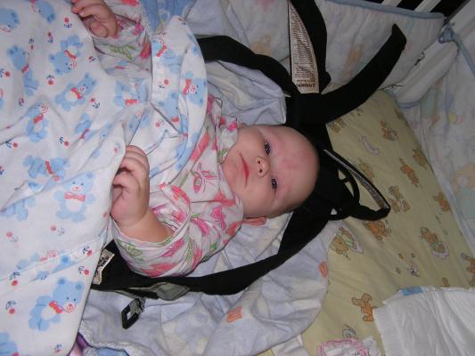 Sarah is awake in her crib in her carier.