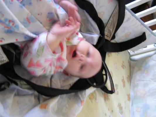 Sarah is awake in her crib in her carier.